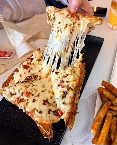 Cheesy Shakti sandwich lifted for a long cheese pull